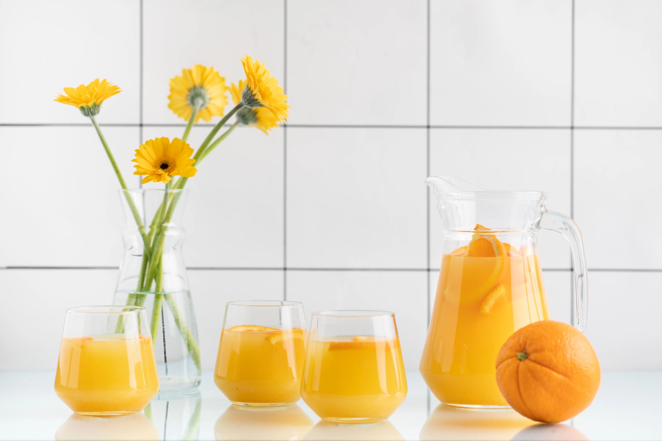 Jugo de naranja recién exprimido en mesa con flores amarillas